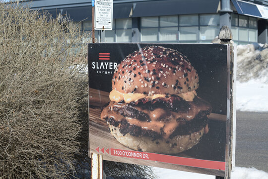 roadside sign featuring a big juicy burger outside Slayer Burger, a restaurant, located at 1400 O'Connor Dr, East York, Toronto
