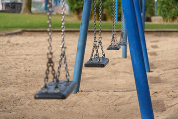 Row of modern empty swings at sandy playground in park of Dusseldorf, Germany