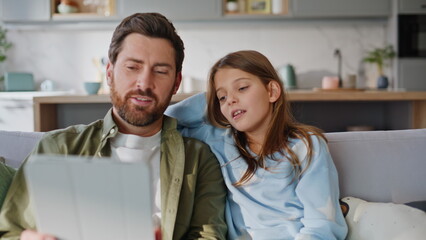 Obraz premium Dad daughter shopping online using tablet home closeup. Smiling father girl