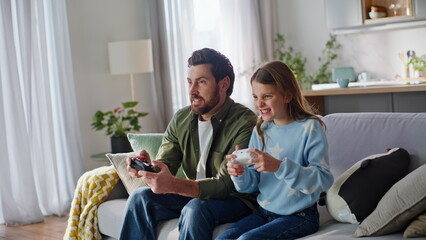 Dad daughter gaming online pressing gamepad on couch. Excited father rejoicing © stockbusters