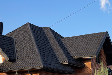 Fototapeta premium Metal Tiling Covers Roof of Modern House Under Clear Blue Sky at Daytime With a Mix of Angles and Shapes Creating a Unique Architectural Style