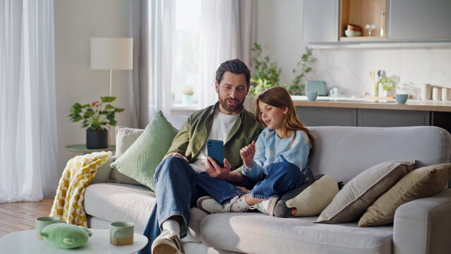 Child parent looking mobile phone starting video call sitting home couch. 