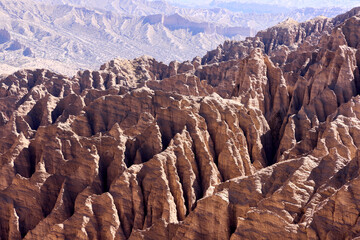Deep erosion carves dramatic spires and peaks across an arid landscape. Sun casts sharp shadows on the unique formations in Valle de las Animas, Bolivia
