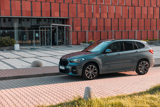 A grey BMW X1 plug-in hybrid SUV is parked on a paved area during a sunny day. Katowice, Poland- 07.30.2021