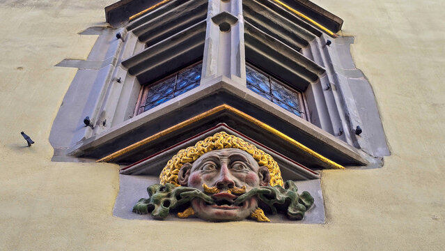View of the fasade element of an old building with Gothic window and a decorative mascaron under the window.
