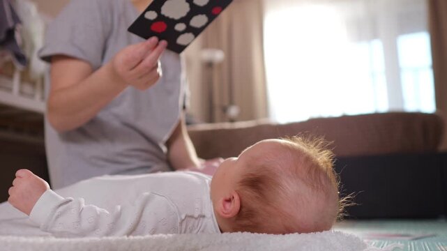 Child Gazes At Contrast Images. Young Baby Observing High Contrast Designs During Playtime. Caucasian Infant Engaged With Visually Stimulating Checkerboard Cards For Developmental Growth