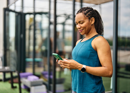 Portrait of a young black woman using a phone ant exting taking a break exercising in a gym, having a training workout in gym, healthy lifestyle and cardio exercise at fitness club concepts