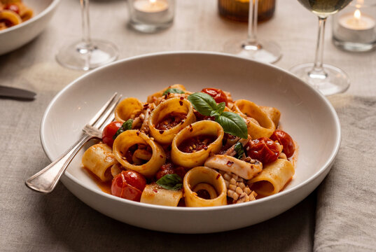 Delicious calamarata pasta with squid and tomato sauce in ceramic bowl