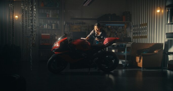 Woman Lovingly Clean Motorcycle in Modern Garage Filled With Golden Light. Female Attentively Polishes Tank and Fairings, Watching Bike Sparkle Beautifully Under Sun Rays. Concept Pride of Ownership.