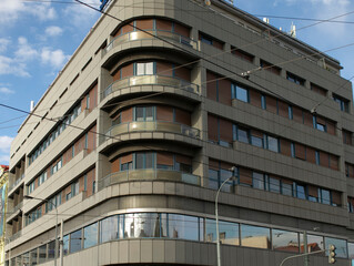 Horizontal banded facade with repeating balconies, urban details and commuter energy. Wide perspective of midcentury office and residential mix,