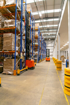 Modern industrial warehouse with narrow aisle pallet racking system and a forklift truck operating between shelves for storing and retrieving palletised goods.