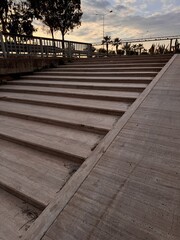 Naklejka premium Concrete outdoor stairs with strong geometric perspective lines. Minimal architectural background with textured stone steps and evening light.