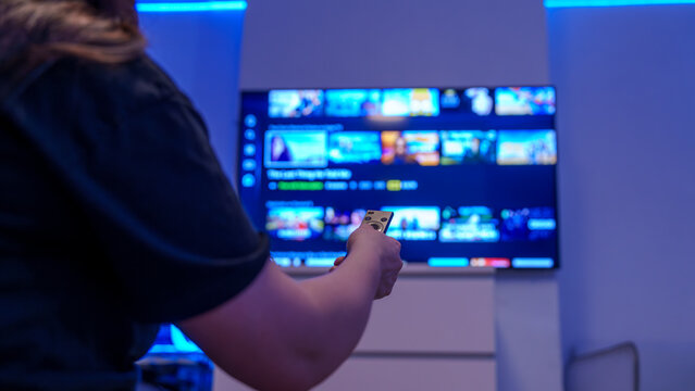 Remote control streaming on smart tv in blue lit living room