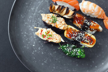 Varied presentation of gourmet Japanese sushi rolls and nigiri pieces with seafood and egg on a dark speckled plate © muse studio