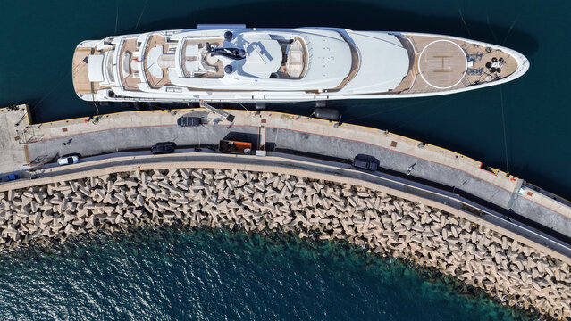 Aerial drone top down photo of luxury yacht with wooden deck and helipad anchored in tropical exotic island port