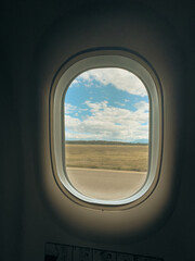 Fototapeta premium view from airplane window during taxiing phase with blue sky, white clouds and grass on the horizon