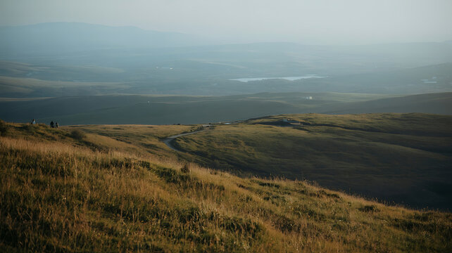 Vast, rolling hills meet a hazy horizon, evoking a sense of solitude and expansive natural beauty.