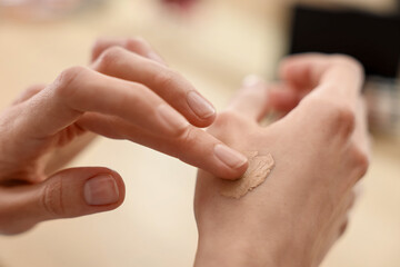 Woman testing foundation on hand indoors, closeup © New Africa