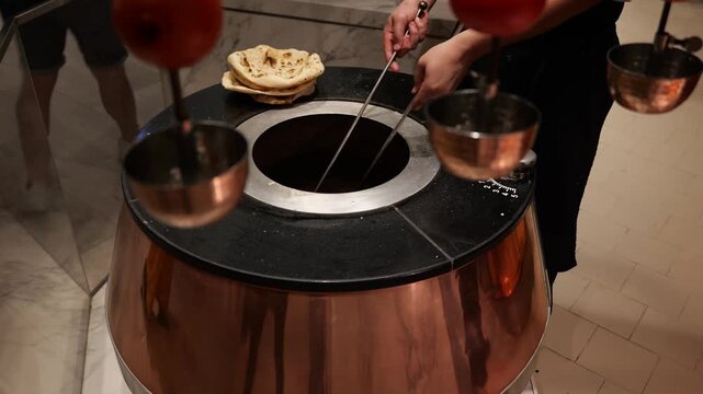 Chef baking naan bread in traditional tandoor oven