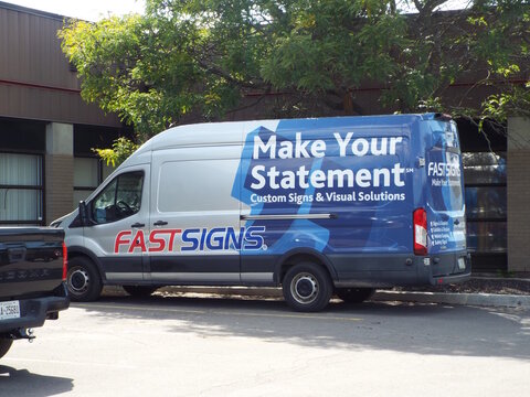 Ottawa, Ontario, Canada-July 17, 2025: A silver and blue "FASTSIGNS" Ford Transit van displays "Make Your Statement" custom signage on Gurdwara Rd.