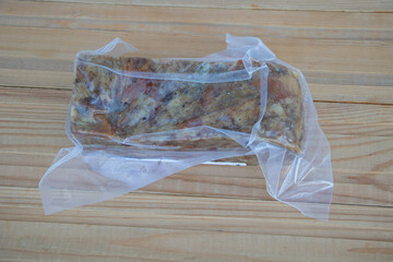 Vacuum Sealed Marinated Meat in Plastic Bag on Wooden Table