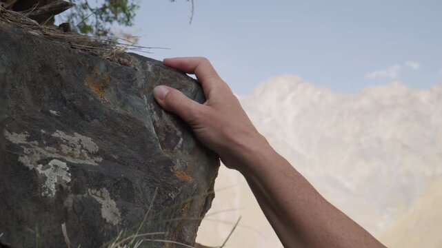Female climber clinging to rock ledges with hands while climbing in mountains