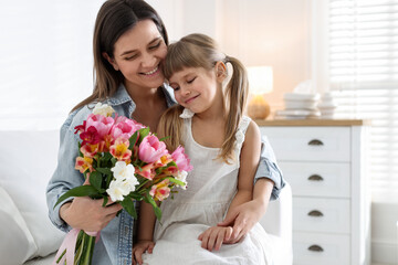 Happy Mother's Day. Mom and her daughter with bouquet of beautiful flowers at home