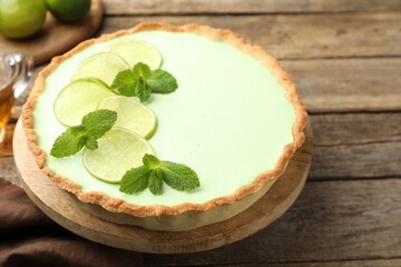 Tasty lime pie with fruit slices and mint leaves on wooden table, closeup © New Africa