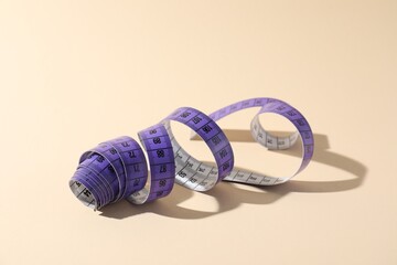 One measuring tape on beige background, closeup