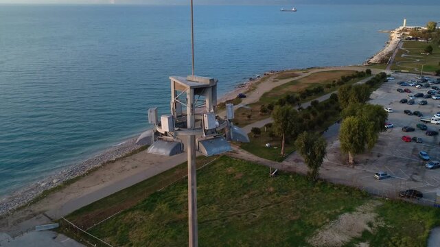 Industrial harbor lighting tower above seaside park and beach