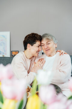 Emotional Adult daughter hugging happy senior 70s mother in cozy interior. Mother day. Happy family enjoying weekend together. Parenting love, care, generations unity. Spending time in retiring house