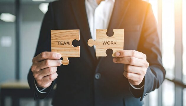 Business Professional Holding Puzzle Pieces Labeled Team And Work Symbolizing Collaboration