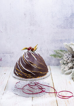 An elegant chocolate Christmas bombe cake with gold leaf accents, white chocolate drizzle