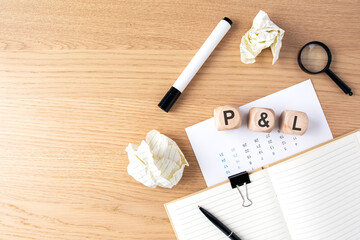 P L Profit and Loss statement concept. Wooden blocks on a desk with magnifying glass, financial...