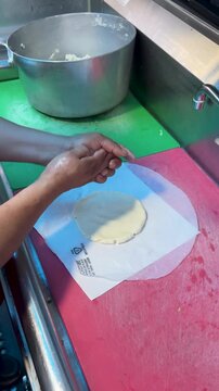 Cook forming a ball of corn masa dough before pressing it into tortillas in a taco truck kitchen.
