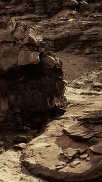 The landscape shows rugged terrain with large rocky formations and scattered pebbles. The ground is dry with minimal vegetation, indicating a harsh environment.