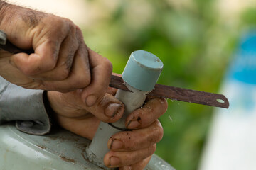 Close-up of a worker using a small handsaw to cut a gray PVC plastic pipe, showing manual labor and...