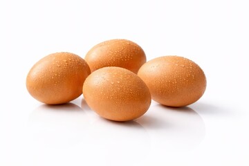Studio photo of four brown eggs with dew droplets on glossy white acrylic and subtle reflection