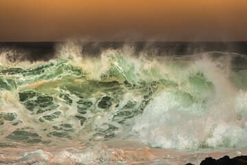 Powerful ocean wave crashing in golden sunset light at Bronte Beach, Sydney, Australia, with...