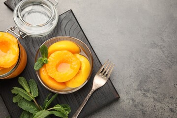 Pickled peaches and mint leaves on grey table, flat lay. Space for text © New Africa