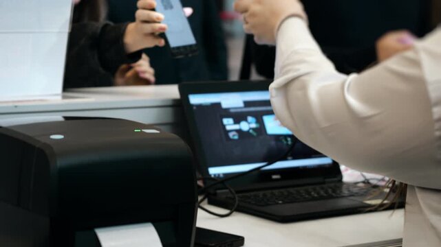 Staff registering attendees and printing name badges at conference registration desk during corporate business event or professional seminar.