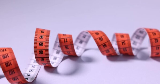 One measuring tape on lilac background, closeup. Camera moving right