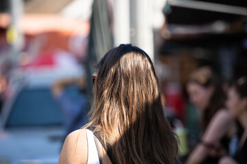 Woman with long bronze hair walking sightseeing in outdoor market, shoulder skin and hair texture,...