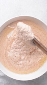 Overhead of moi moi mixture in a white ceramic bowl, top view of nigerian bean pudding being mixed, process of making nigerian moi moi