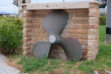 an antique propeller on a brick wall © Natalia