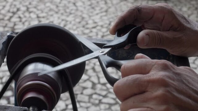 Close-up of a worker's hands. Tool sharpener. Informal worker on the street sharpening scissors.