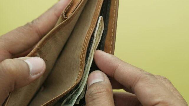 Person pulling money from wallet, close up on hands and american currency inside a brown leather wallet