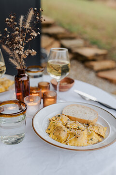 Butternut squash ravioli with brown butter sauce for dinner on a patio.