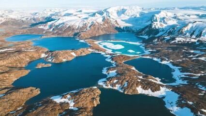 Obraz premium Aerial view of snow-covered mountains and turquoise lakes in a remote Arctic landscape