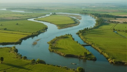 Aerial view of a winding river flowing through lush green agricultural fields
